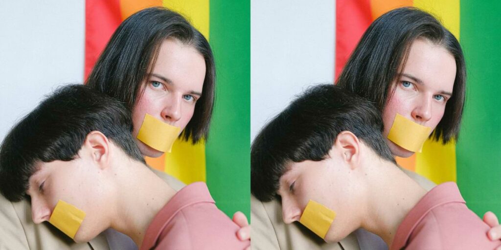 Image of two men with taped mouths in front of a pride flag used to represent corporate silence and dehumanization
