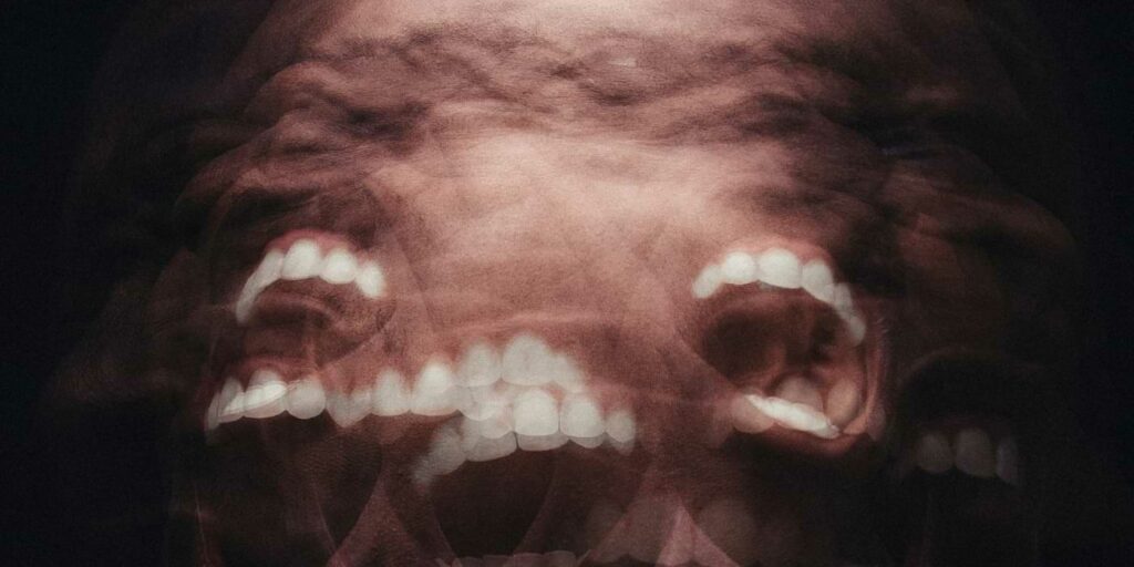 Image of dehumanization depicted by frantic overlapping teeth in a chaotic image of destabilization